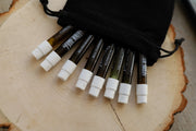 Assorted cosmetic sticks with white caps and black sleeves, on a round wood slice.