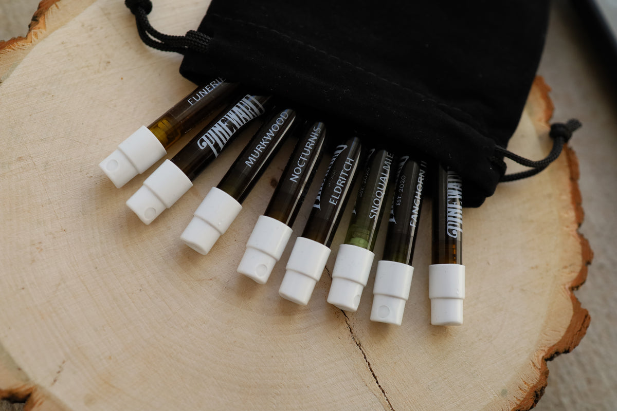 Assorted cosmetic sticks with white caps and black sleeves, on a round wood slice.