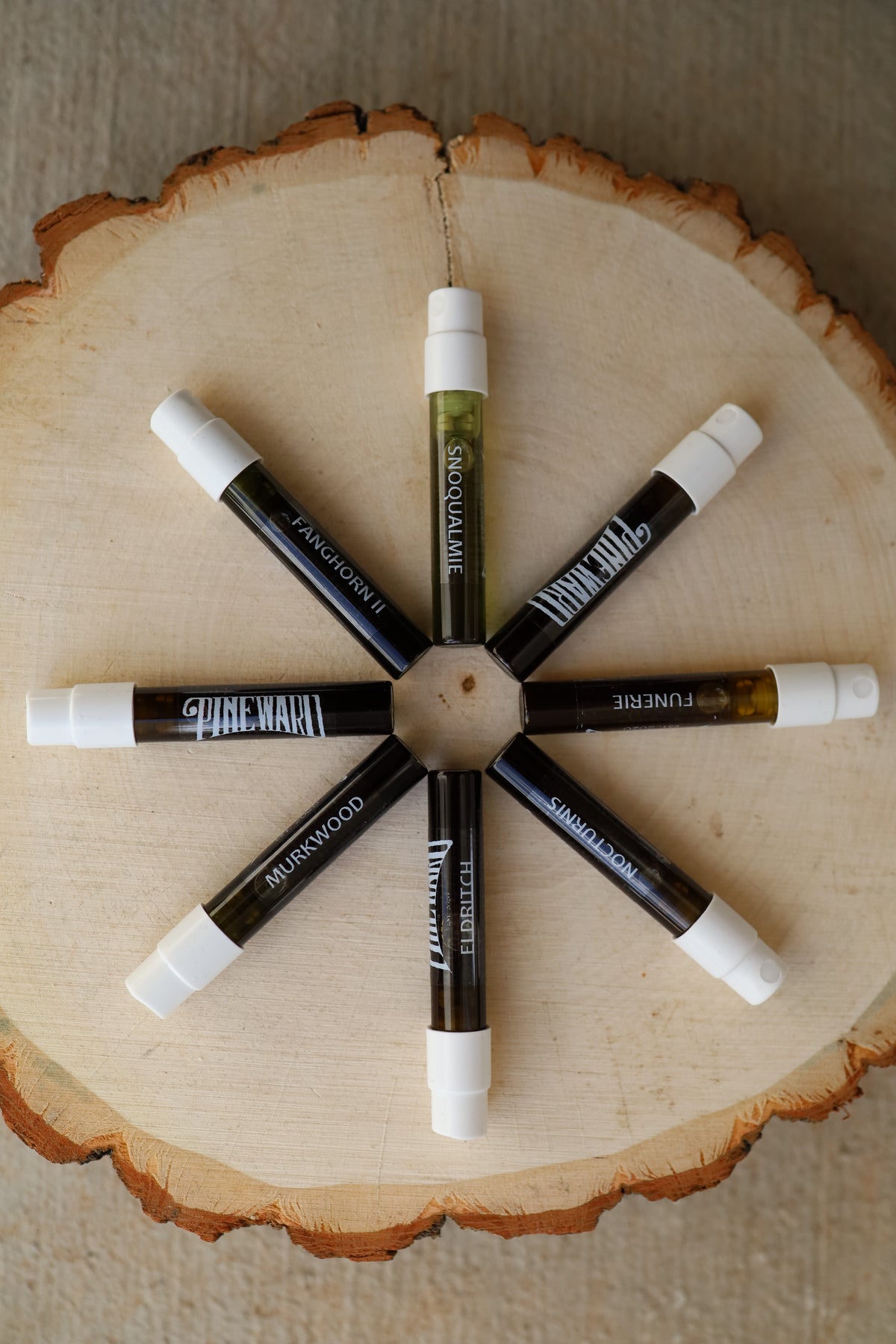 Cosmetic stick set with white caps arranged in a star on a round wood slice.