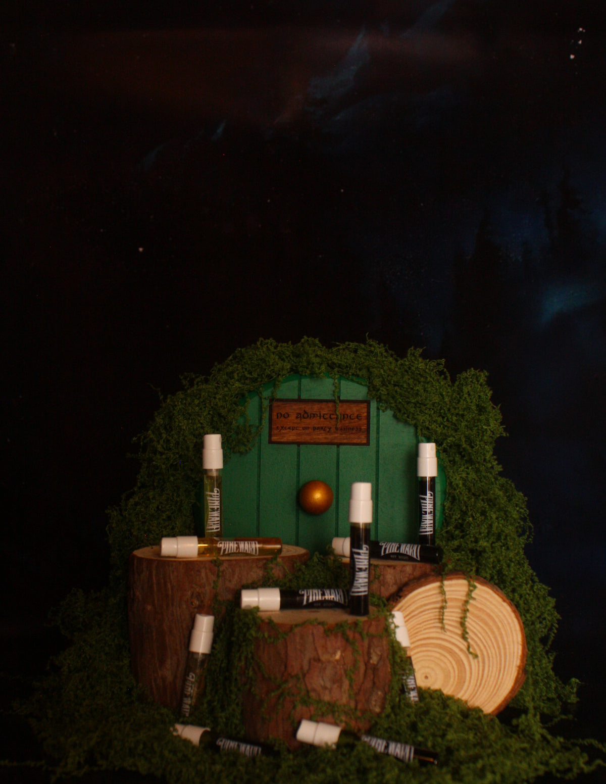 Gift set display with several bottles, moss circle backdrop, and wooden log pieces
