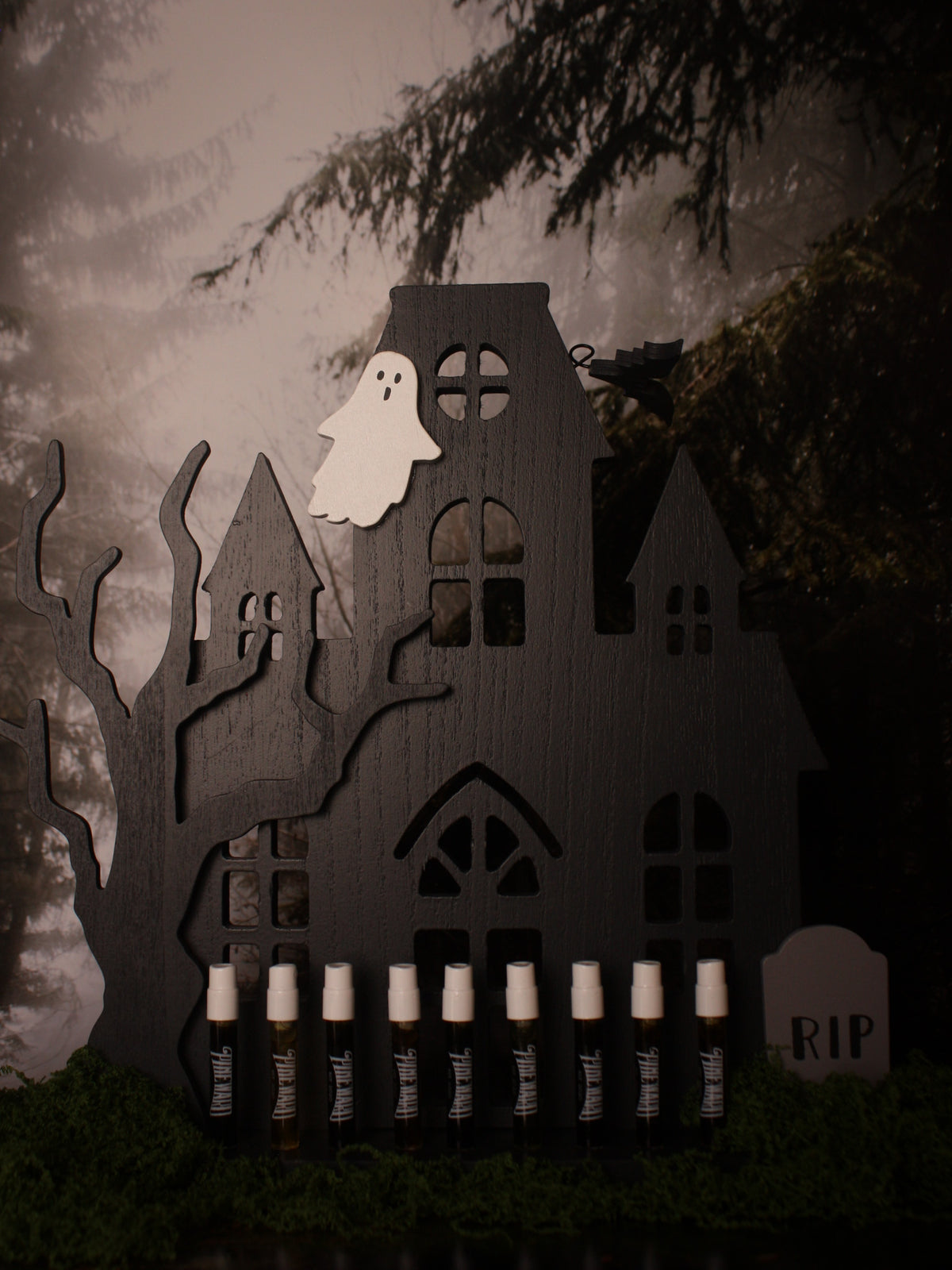Haunted house candle display with cutout buildings, cylinder candles, and 'RIP' sign